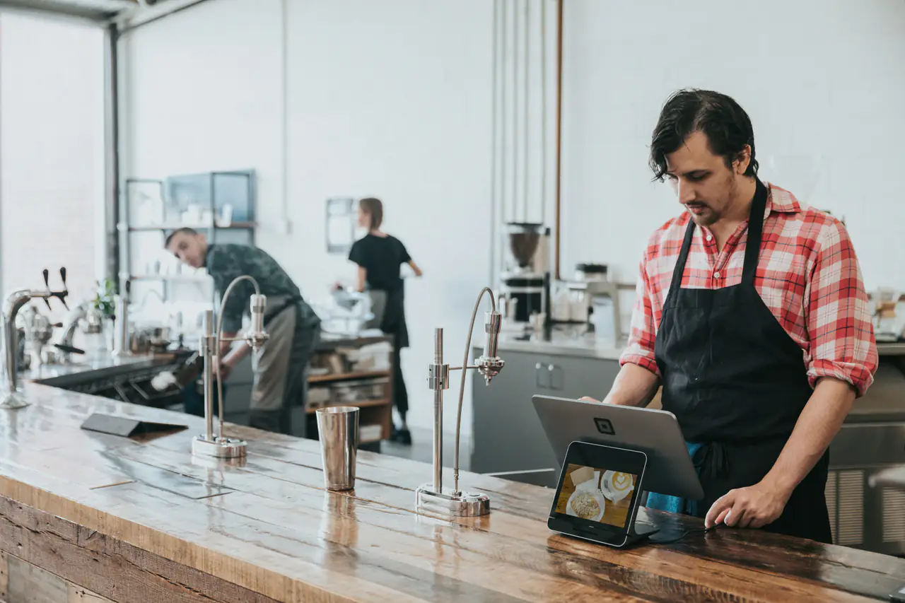 Barista qui consulte une tablette derrière son comptoir