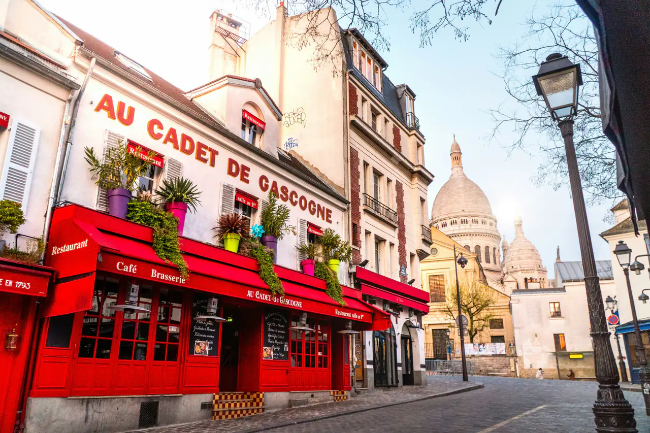 Façade rouge d'un restaurant à Montmartre, le Sacré-Cœur en fond